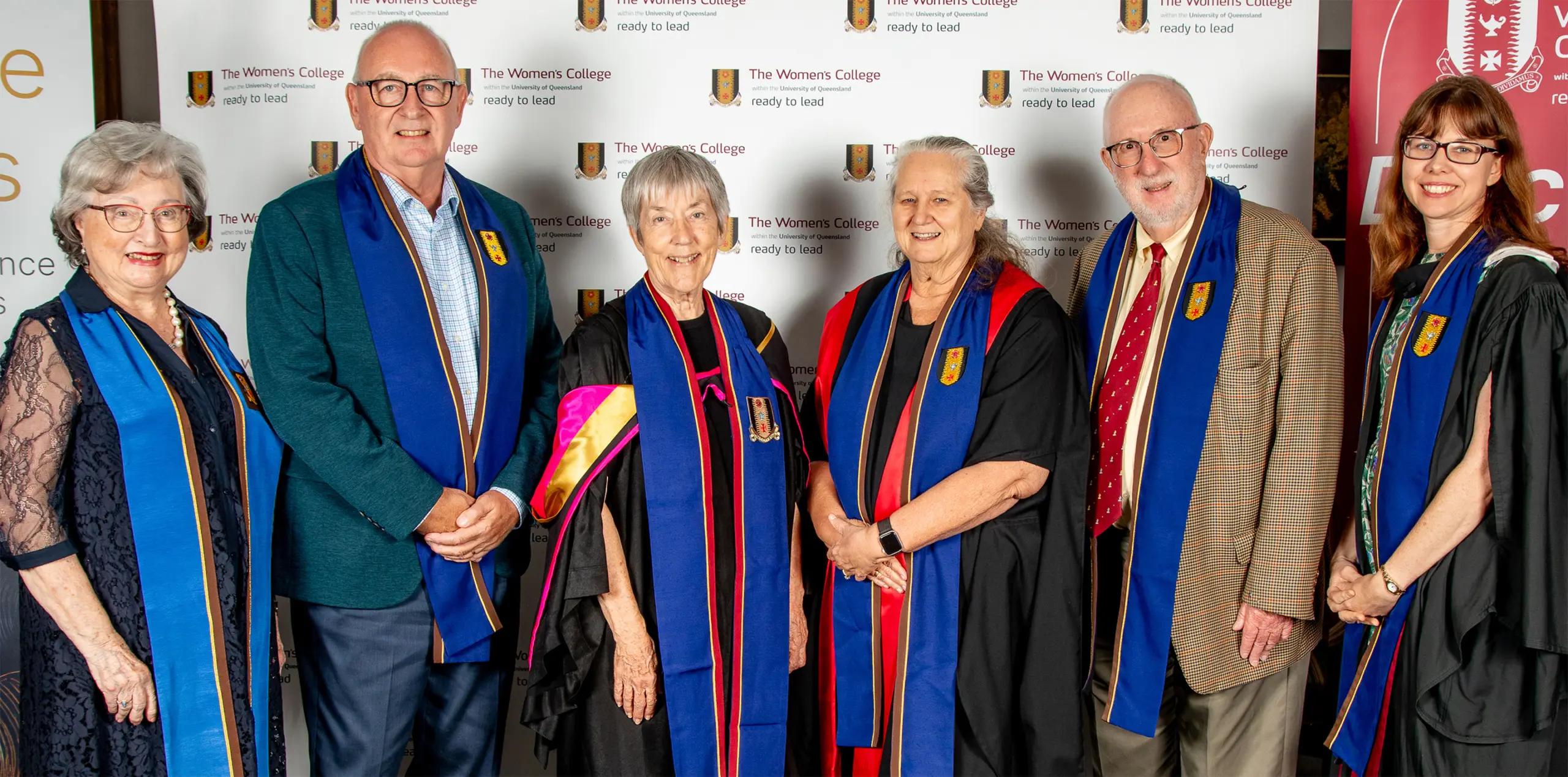 A group of six people stand together in academic dress.