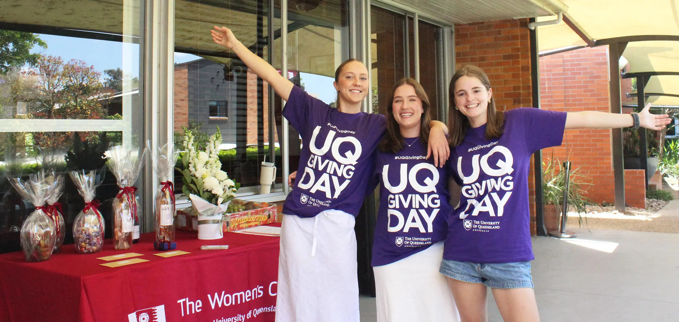 Three students pose for a photo in purple UQ Giving Day shirts.