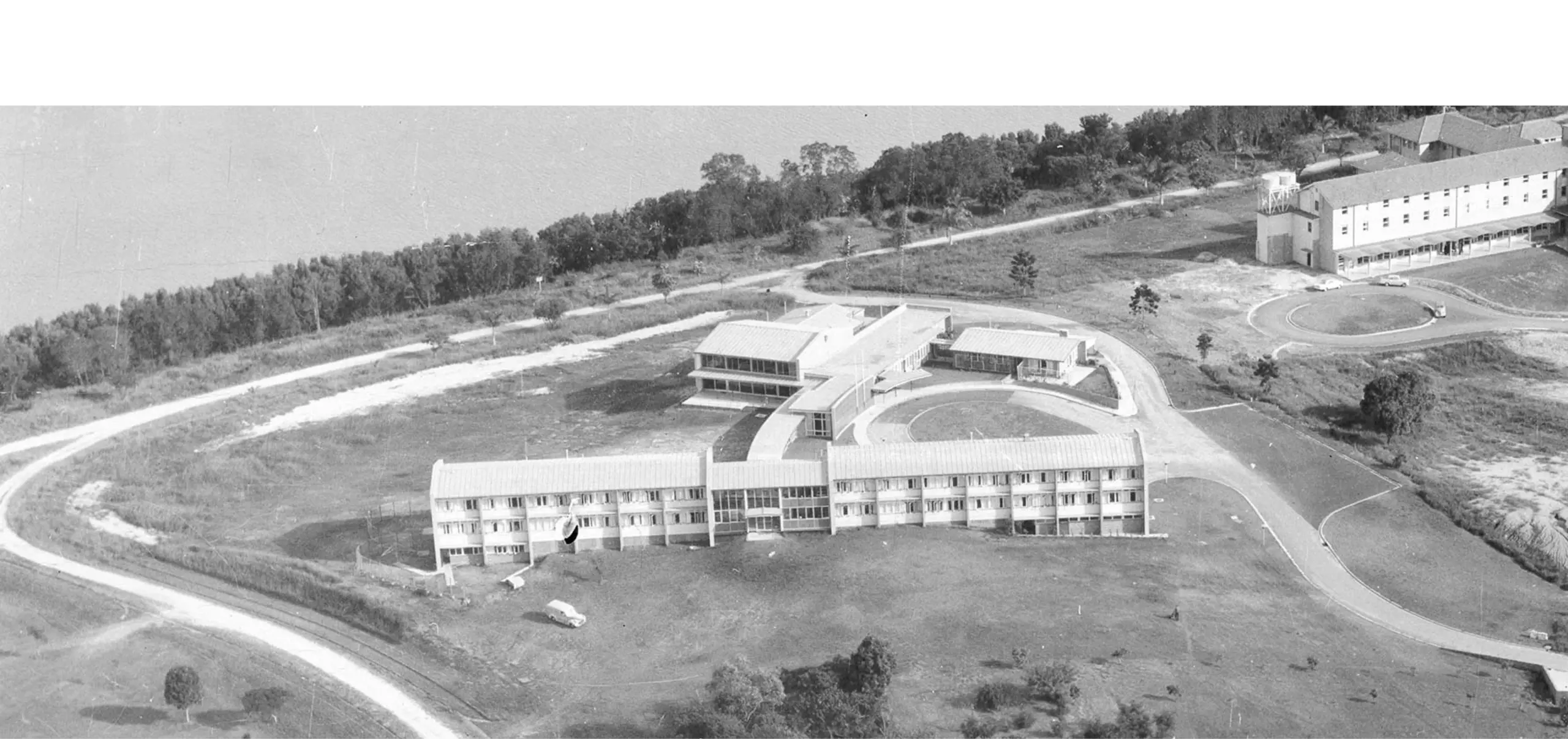 An aerial black and white photo of a building next to a river.