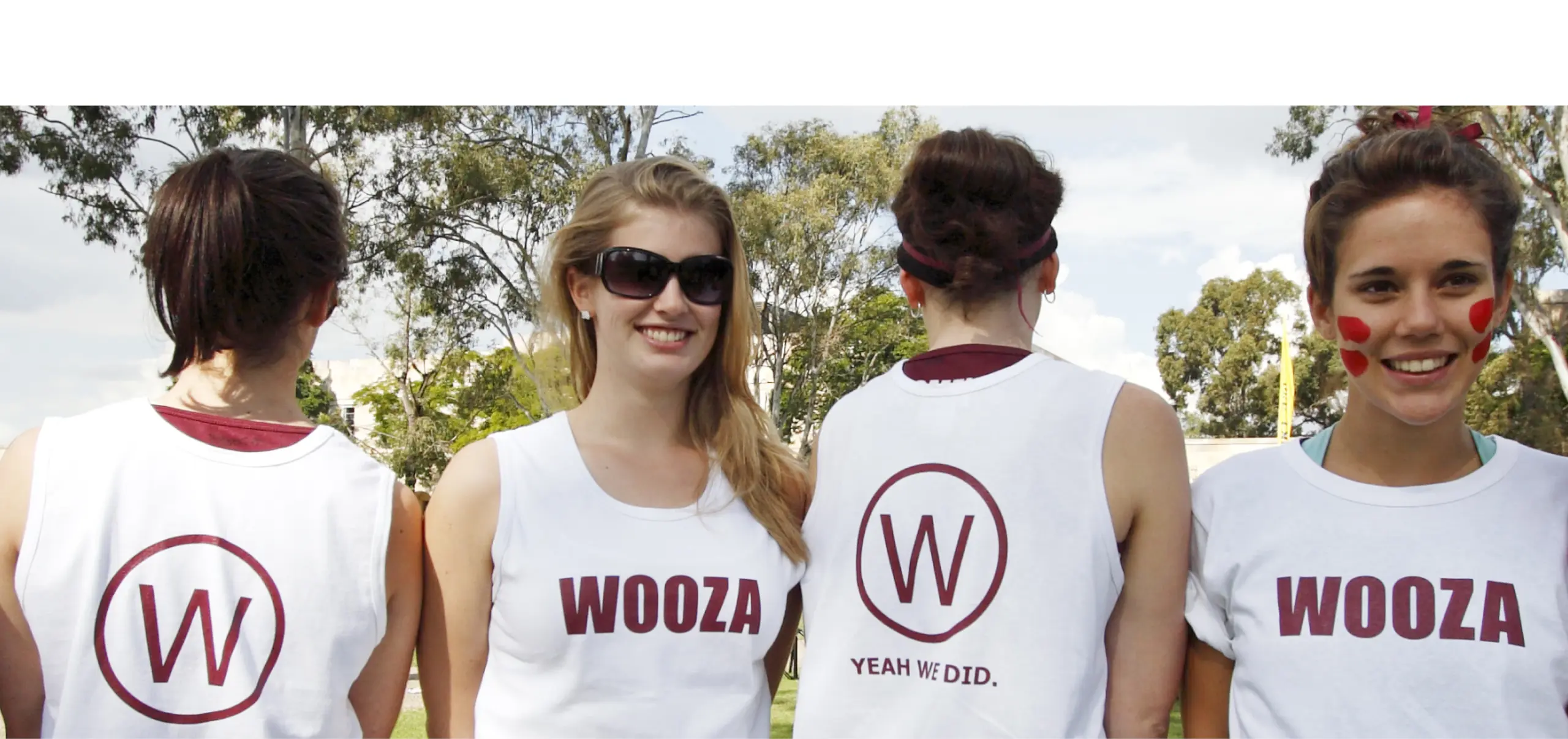 A colour photo of four people wearing white singlets, two facing the camera and two with their backs to the camera.
