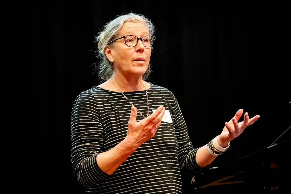 A close-up photo of a lecturer against a black background.