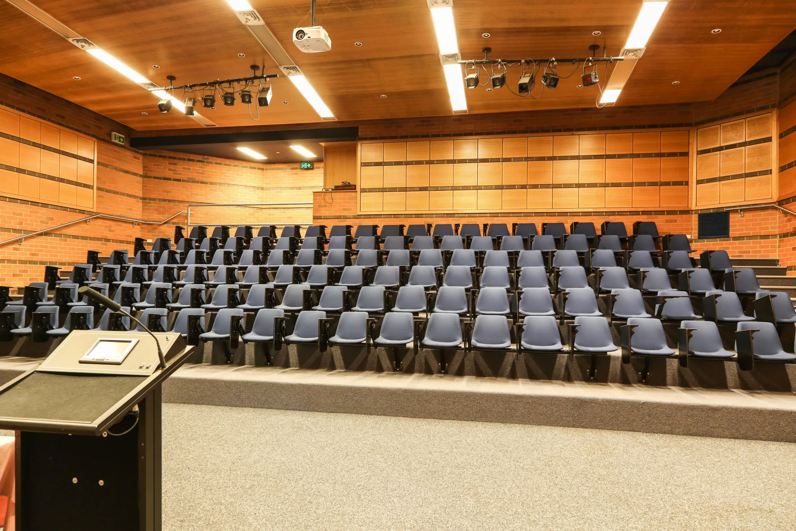 A photo of the tiered seating in a lecture-theatre style auditorium. The chairs are blue.