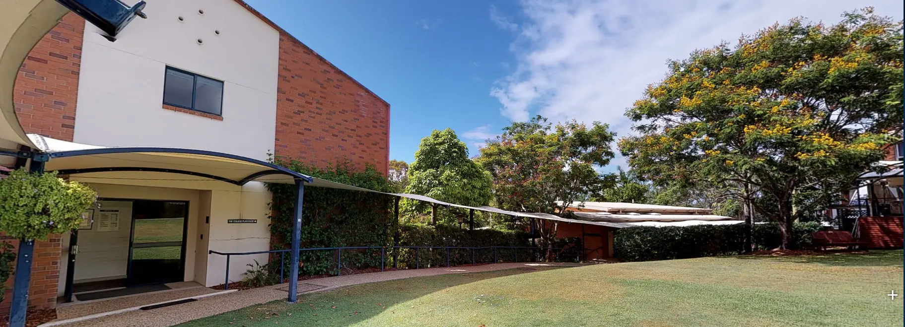 A panoramic photo of a building and surrounding garden areas.