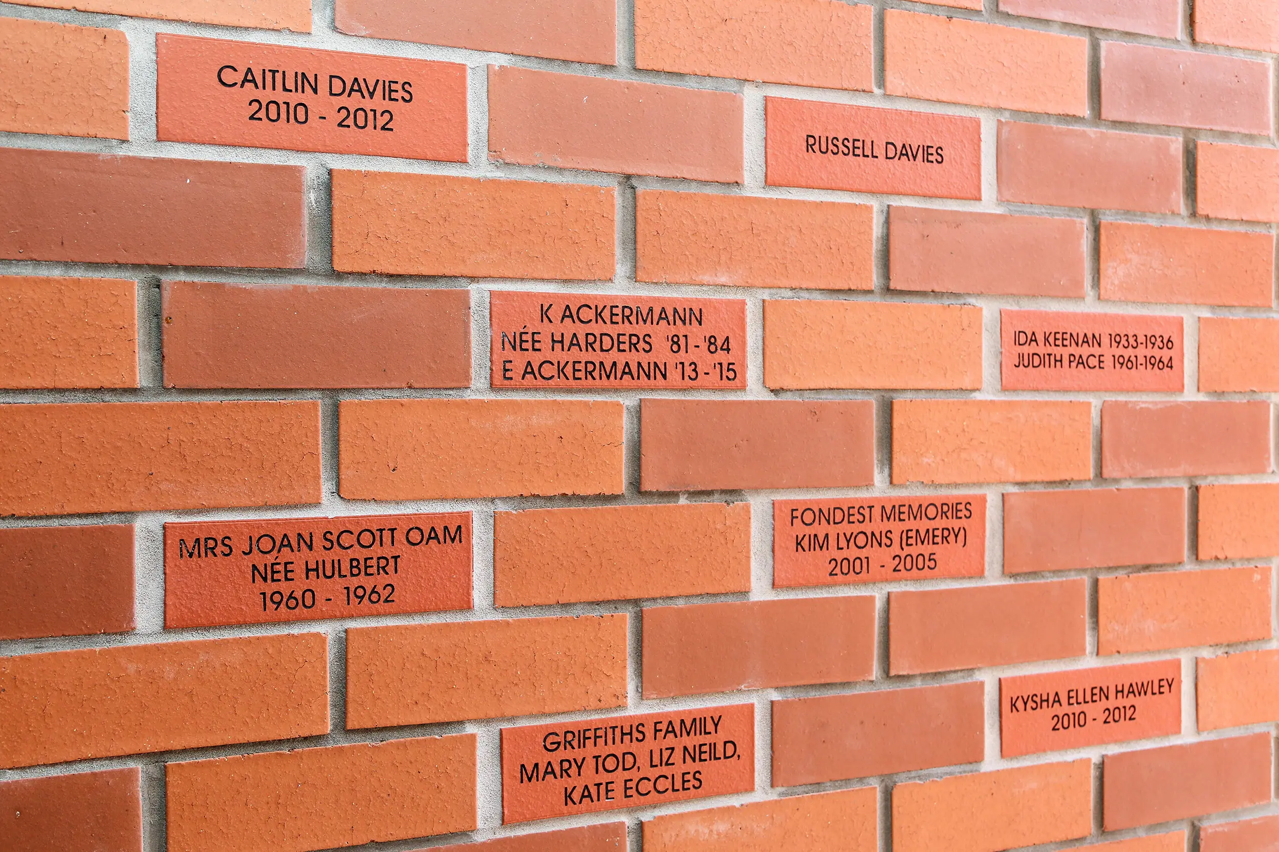 A brick wall where some of the bricks are engraved with the names of donors.