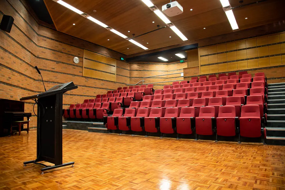 The inside of an auditorium where the chairs are red.